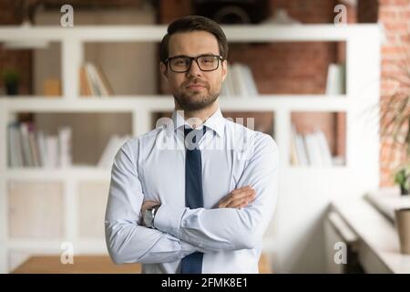 Tête portrait homme d'affaires confiant dans des lunettes debout au bureau Banque D'Images