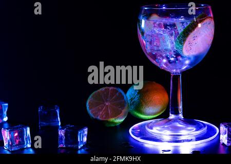 Gin Tonic cocktail dans un verre avec un citron vert et glaçons Banque D'Images