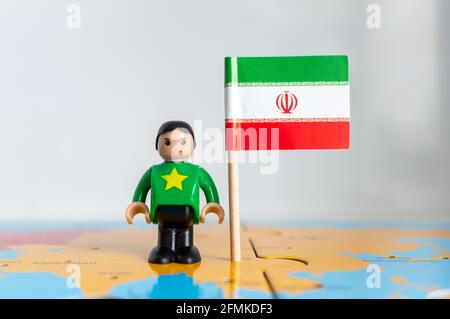 POZNAN, POLOGNE - 06 avril 2021 : figurine jouet joutive située à côté d'un drapeau national de l'Iran. Banque D'Images