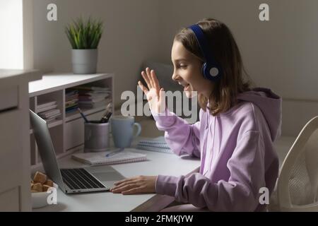 Bonne petite adolescente dans un casque pour commencer un appel vidéo. Banque D'Images