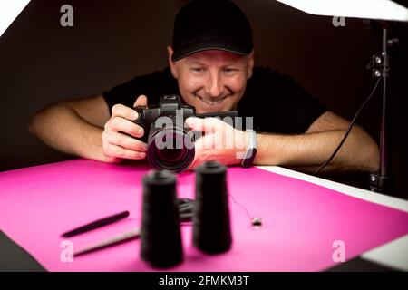 Un photographe qui prend une photo des accessoires de confection noirs dans le studio Banque D'Images