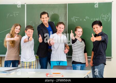 L'école et l'éducation - l'enseignant et les étudiants sont devant un tableau noir avec des maths travailler dans une salle de classe ou classe Banque D'Images