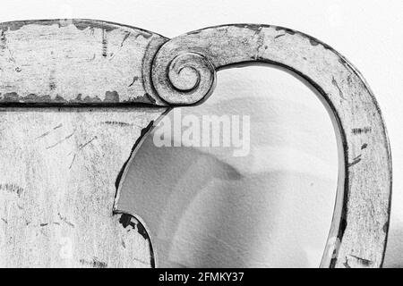 Une partie d'une ancienne chaise en bois courbe projette des ombres sur le mur blanc derrière elle. Banque D'Images