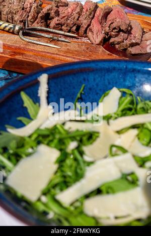 Un délicieux déjeuner en plein air composé de plats de bœuf rares et salade de parmesan et de roquette Banque D'Images