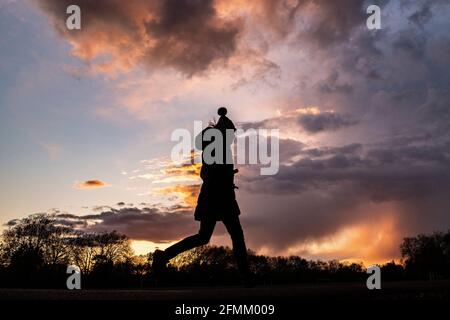 Une fille rentre à la maison au coucher du soleil en portant un chapeau de galet Banque D'Images