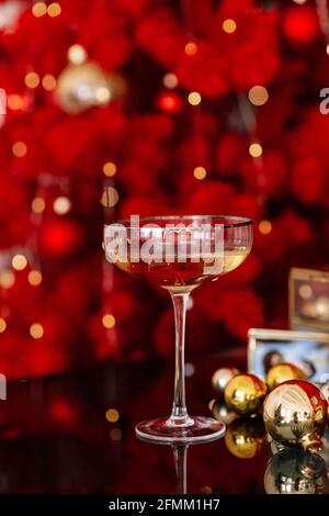 Bonne année 2021. Vacances de Noël et du nouvel an rouge arrière-plan minimal, saison d'hiver. Un verre de champagne sur fond de lumières bokeh. Banque D'Images