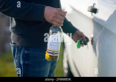 Ivre en charge d'un camping-car. Un homme déverrouille la porte de sa camionnette avec une bouteille d'alcool de whisky dans sa main. Buvez conduire Angleterre Royaume-Uni Banque D'Images