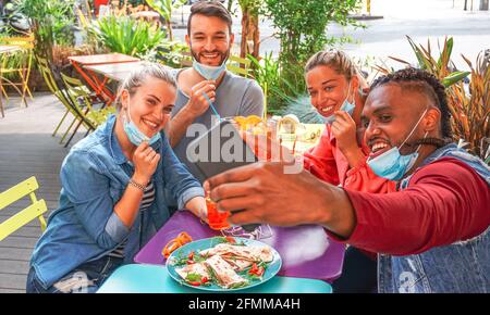 Des amis prenant le selfie dans un bar-restaurant avec masque de visage On en temps de coronavirus - les jeunes s'amusent avec boissons et en-cas dehors avec nouvelle règle Banque D'Images