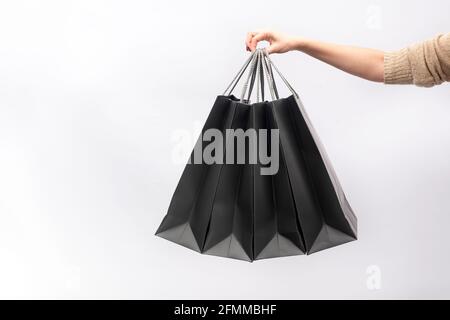 La main femelle tient des sacs de shopping en papier noir isolés sur blanc arrière-plan Banque D'Images