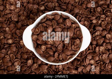 flocons de chocolat dans un bol sur fond de flocons, concept de petit déjeuner sain, assiette de flocons de maïs Banque D'Images