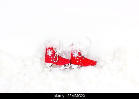 Chaussures de patinage en peluche vintage rouge vif sur fond de neige artificielle blanche avec espace de copie. Sports d'hiver, Noël et le concept de vacances de nouvel an Banque D'Images