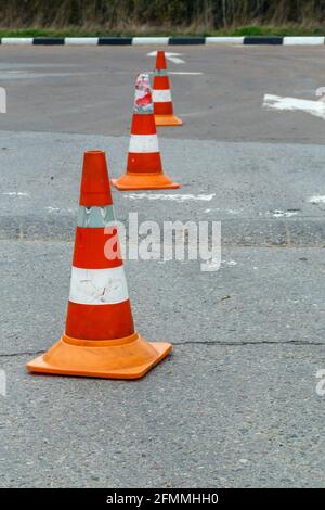 cônes de signalisation orange sur chaussée en asphalte gris sec - gros plan avec mise au point sélective. Banque D'Images