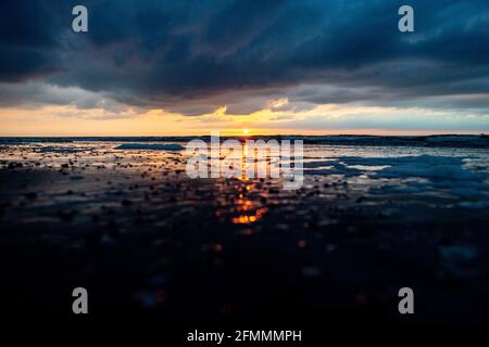 Norderney, Allemagne. 10 mai 2021. Le soleil se couche sur la mer du Nord à la plage 'Weiße Düne' et se reflète dans les vagues. Credit: Hauke-Christian Dittrich/dpa/Alay Live News Banque D'Images