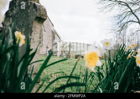 traversez la pierre tombale dans une cour d'église entourée de fleurs Le Royaume-Uni Banque D'Images