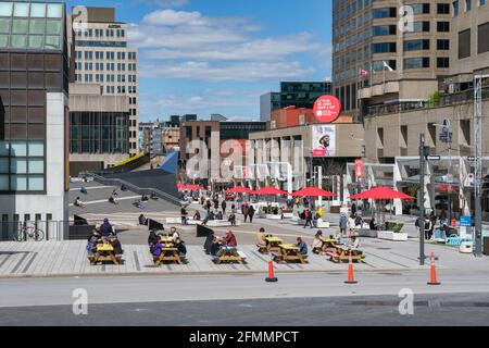 Montréal, CA - 6 mai 2021 : personnes assises aux tables de pique-nique de la rue Ste Catherine, au centre-ville de Montréal. Banque D'Images