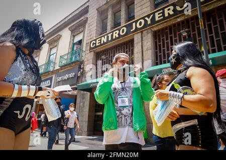 Mexique, Mexique. 10 mai 2021. Un colporteur porte un masque qui lui est donné par les Luchadores mexicains. « la Brigade deux des trois chutes », appelée par le Mexican City Youth Institute, a fait un tour de Madero Street dans le centre historique en encourageant l'utilisation de masques de visage puisque la pandémie continue malgré le feu de circulation jaune épidémiologique. Crédit : SOPA Images Limited/Alamy Live News Banque D'Images