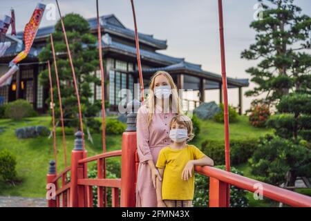 Mère et fils voyageurs dans un masque médical regardant le bâtiment traditionnel japonais. Les touristes voyagent au Japon après l'épidémie de coronavirus Banque D'Images