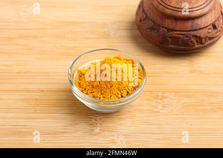 Poudre de curcuma dans un bol en verre sur fond de bois. Banque D'Images