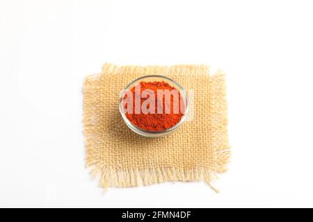 Poudre de piment rouge dans un bol en verre sur fond blanc. Banque D'Images