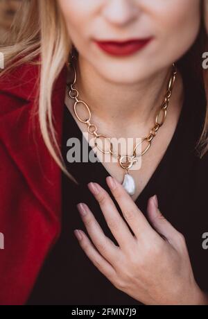 Belle jeune femme blonde dans une robe d'automne tendance de couleur bordeaux Marsala avec un collier sur son cou. Mise au point sélective douce. Bruit artistique. Banque D'Images