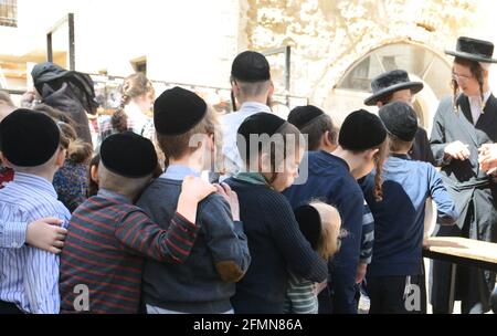 Des enfants orthodoxes juifs attendent en file pour de la nourriture et des bonbons servis par un homme juif juste pendant les préparatifs de la Pâque à MEA She'arim Jérusalem. Banque D'Images