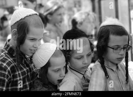 Des enfants orthodoxes juifs attendent en file pour de la nourriture et des bonbons servis par un homme juif juste pendant les préparatifs de la Pâque à MEA She'arim Jérusalem. Banque D'Images