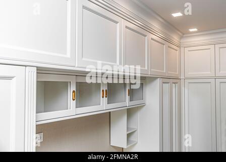 armoire blanche de style classique avec portes vitrées coulissantes et dorures se porte sur le fond de rideaux bordeaux avec un motif floral répétition Banque D'Images