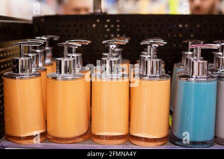 distributeurs de savon en plastique coloré alignés sur la tablette du magasin Banque D'Images