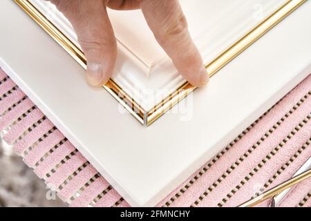 Les employés colles élégante bande décorative de moulage dorée sur le mobilier blanc panneau de façade de style classique en atelier de très gros plan Banque D'Images