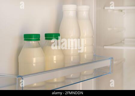 Bouteilles blanches avec couvercle vert de yaourt sur la grille du réfrigérateur vide ouvert. Concept de régime de perte de poids. Aliments fermentés. Banque D'Images