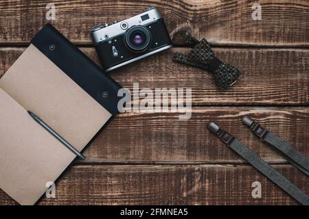 fête des pères avec des accessoires pour hommes noeud papillon, portefeuille, appareil photo rétro, bretelles et bloc-notes sur fond de bois. Copier l'espace. Pose à plat. Banque D'Images