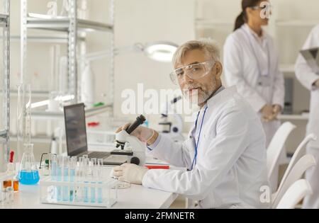 Portrait d'un scientifique expérimenté et expérimenté qui travaille au microscope dans un laboratoire. Banque D'Images