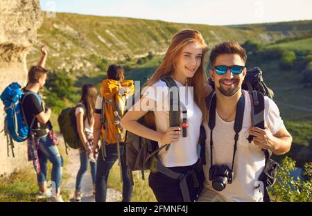 Jeunes randonneurs souriants debout avec des sacs à dos et un appareil photo groupe et rochers paysage à l'arrière-plan Banque D'Images