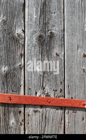 Gros plan d'une vieille porte en bois avec barre de verrouillage rouillée. Banque D'Images