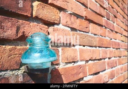 Gros plan d'un ancien isolant électrique en verre sur un mur de briques, mise au point sélective. Banque D'Images