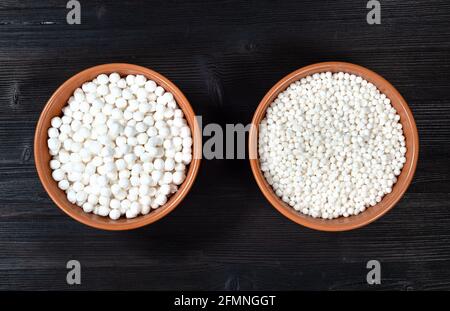 vue de dessus de deux bols en céramique avec divers tapioca sago perles sur table en bois noir Banque D'Images