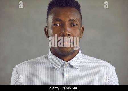 Studio portrait d'un jeune homme afro-américain sérieux en chemise blanche regarder l'appareil photo Banque D'Images