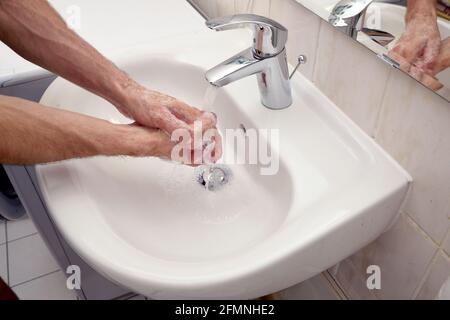 un jeune homme se lavant les mains pour prévenir la propagation de la maladie du virus de la coronie - savon, eau, déinfection qui coule à la maison Banque D'Images