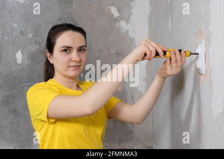 Une femme réparateur dévisse une douille de tournevis. Réparations dans la maison par elles-mêmes. Fixation des grilles électriques Banque D'Images