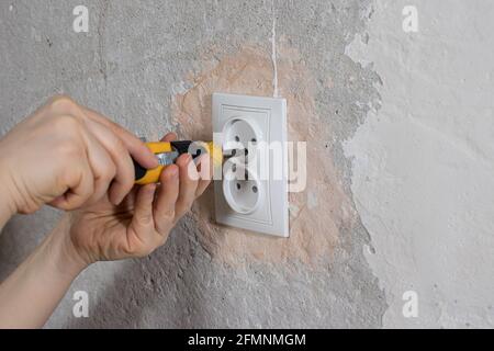 Un réparateur de mains dévisse une douille de tournevis. Réparations dans la maison par elles-mêmes. Fixation des grilles électriques. Services d'électricien Banque D'Images