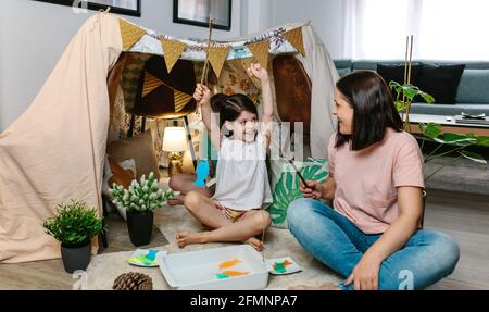 Fille heureuse de gagner sa mère dans un jeu de pêche pendant le camping à la maison Banque D'Images