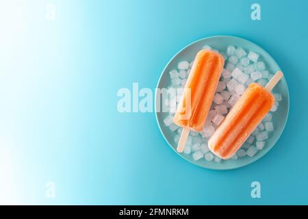 Pop-sicles orange sur plaque bleue sur fond bleu Banque D'Images