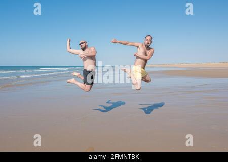 des amis sautant et s'amusant sur une plage isolée par une journée ensoleillée. amitié, union, loisir et concept de vacances Banque D'Images