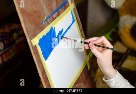 La main de l'enfant retient le pinceau et les peintures sur toile, mise au point sélective Banque D'Images