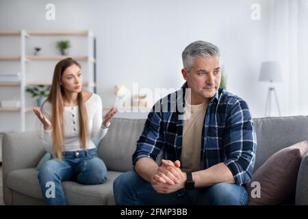 Couple mature marié ayant luttés, une femme en colère arguant avec l'homme malheureux dans le salon, espace de copie Banque D'Images