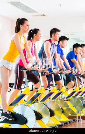 Sport asiatique chinois groupe d'hommes et de femmes dans le club de remise en forme ou de sport sur l'exercice de vélo Banque D'Images