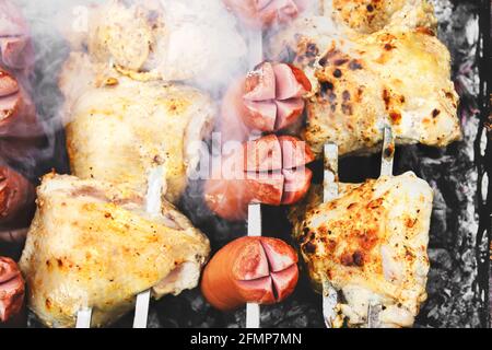 Les saucisses sont frites sur le gril. Viande grillée. Ailes de poulet Banque D'Images