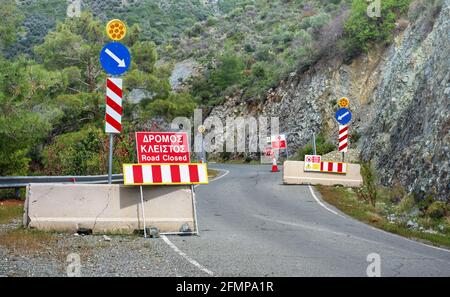 Route en réparation dans les montagnes Troodos, Chypre. Panneaux indiquant les arrêts et les routes fermées en anglais et en grec Banque D'Images