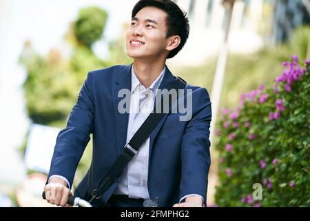 jeune homme d'affaires asiatique à vélo pour aller travailler ou en aller, heureux et souriant Banque D'Images