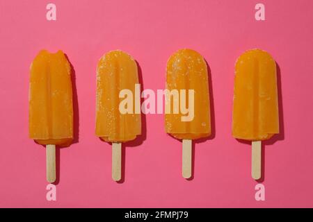 Bâtonnets de glace au mangue ou au caramel sur fond rose Banque D'Images